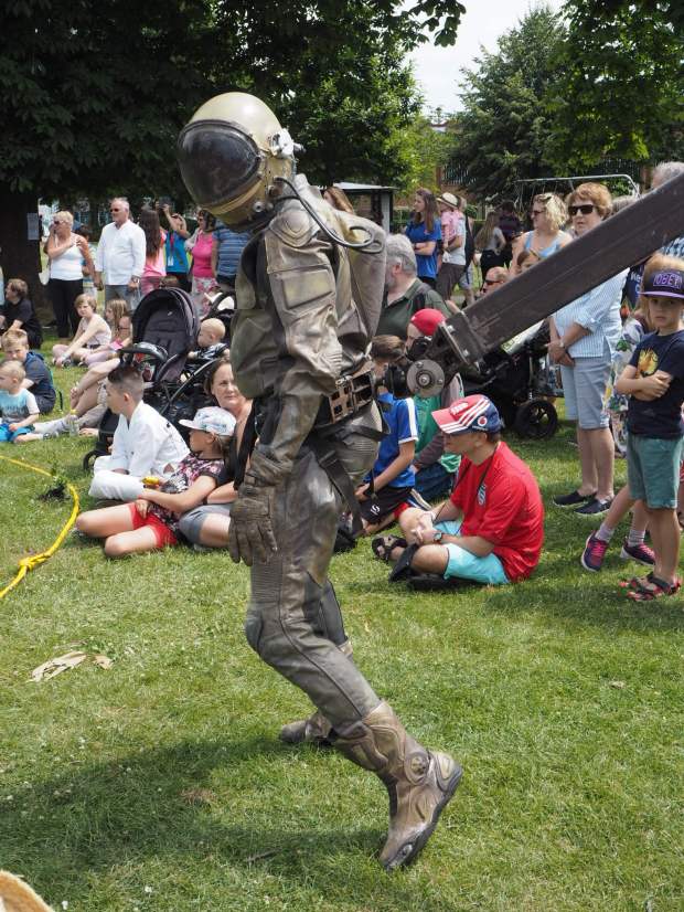 A man in a khaki astronaut outfit arrives into the crowd