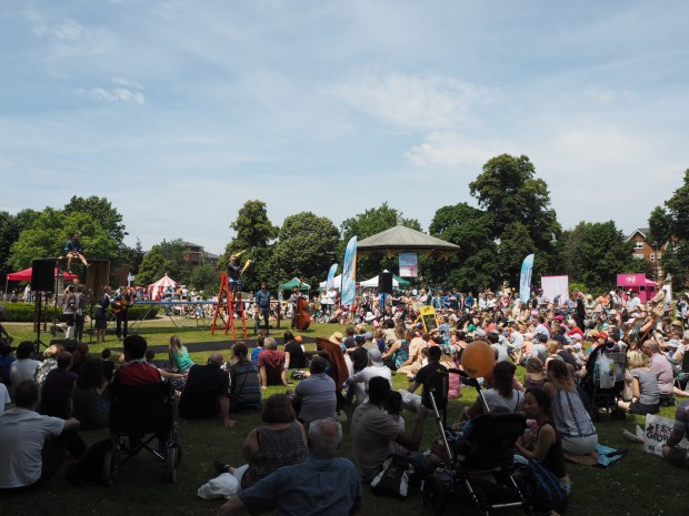 Street performance - acrobats perform on a trampoline in front of a crowd in the sun