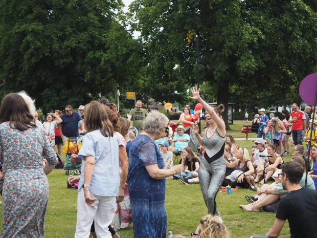 A lady in sequins leads people in a disco dancing session in the park