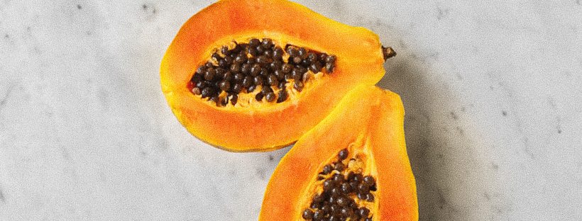 papaya, cut in half, on a marble surface