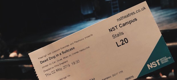 a ticket for a theatre show held up in front of an empty stage