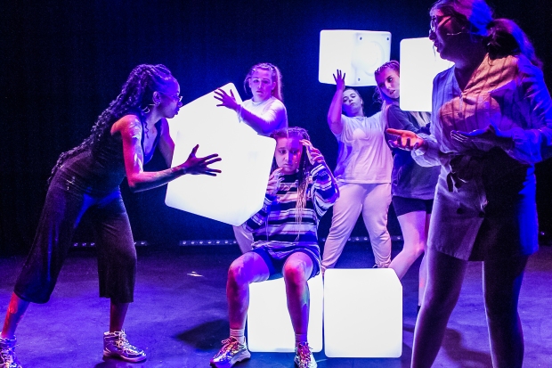 Young actors on stage playing with illuminated cubes