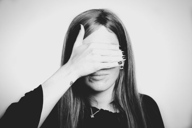 Black and white photo of a woman with long hair covering her eyes with her right hand