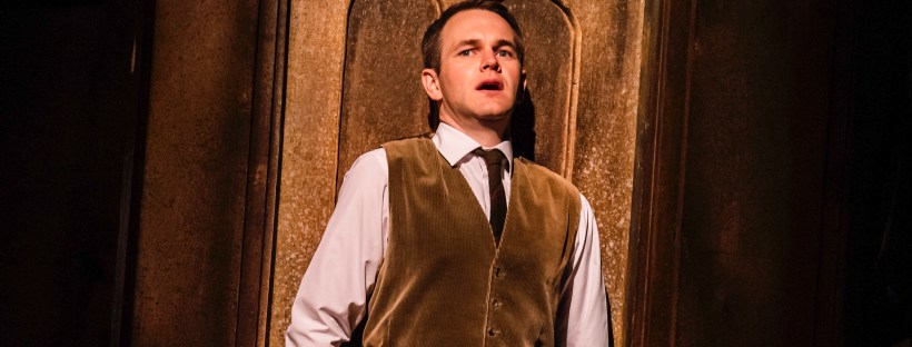 An actor looks on in horror, with his back to a dark door