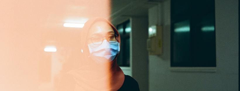An overexposed film image of a woman wearing a facemask