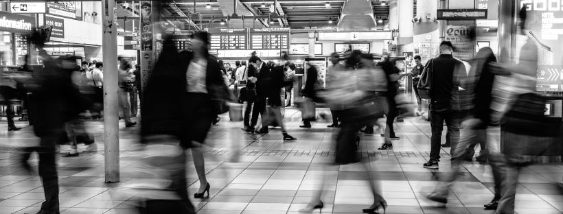 A grayscale, blurry photo of people rushing at a station in Japan