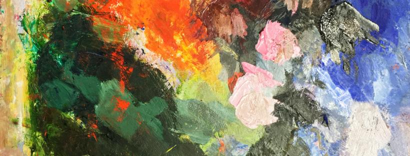 A palette covered in messy but colourful oil paints